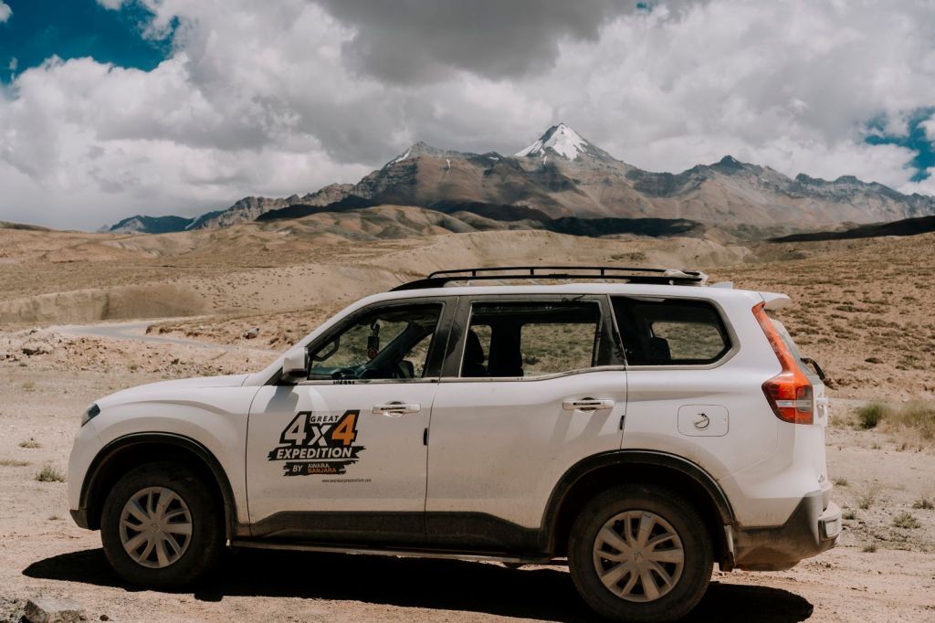 An off-road vehicle on a dirt track below mountains