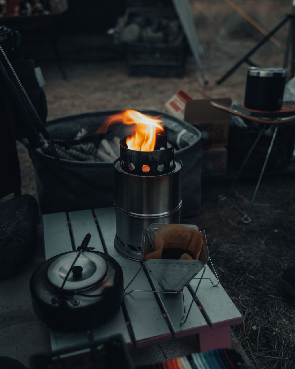 A portable camp stove burning on a table outdoors