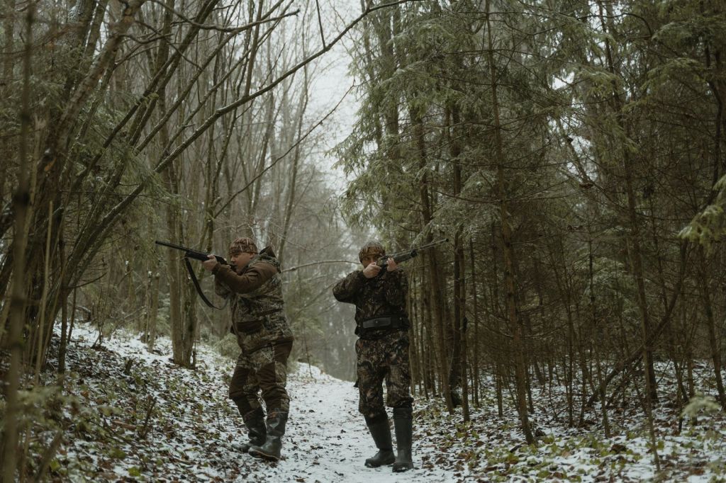 Two hunters walking through bare winter woods