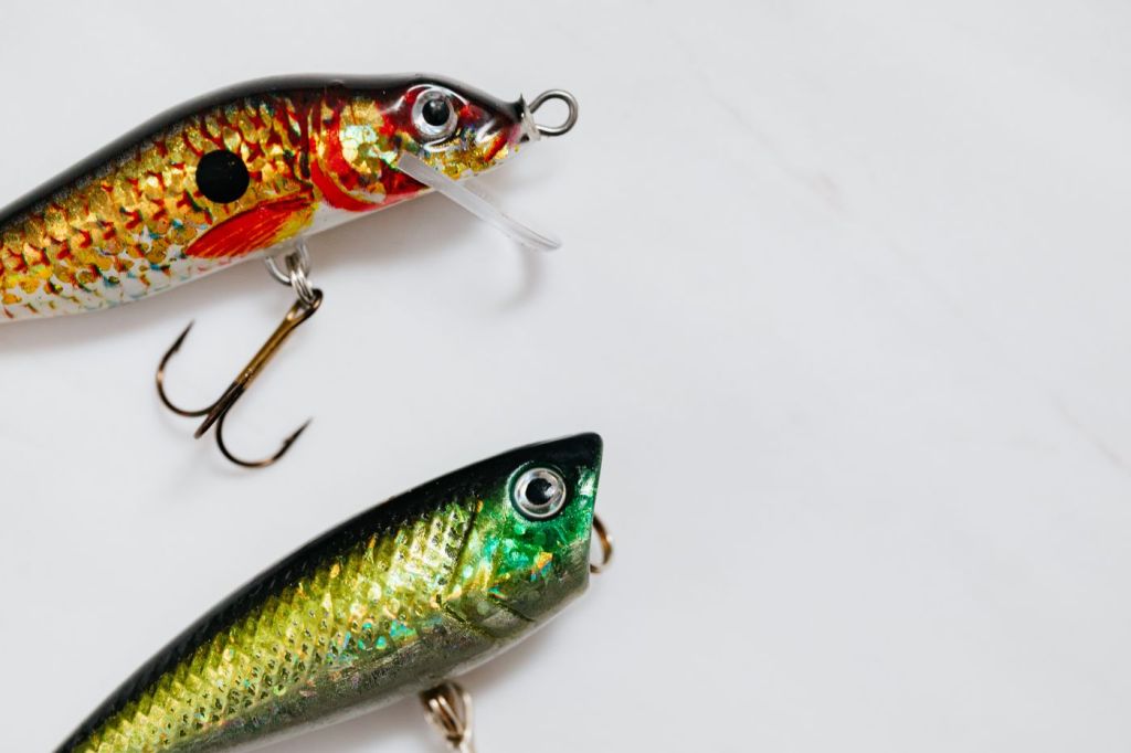 Two fishing lures with treble hooks on a white surface
