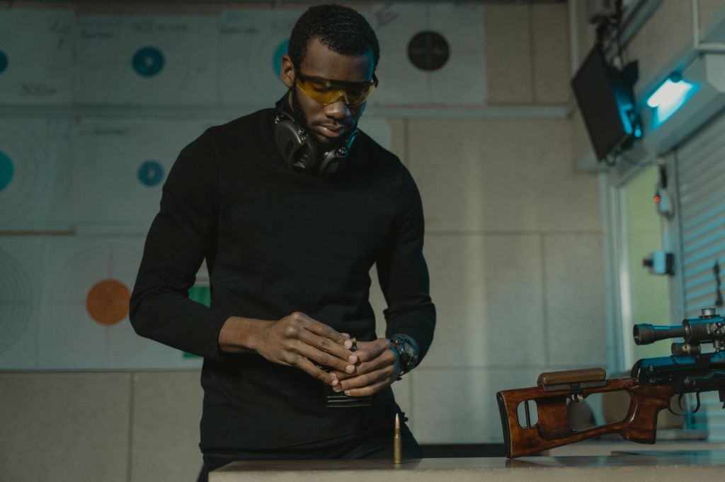 A shooter wearing safety glasses loading rifle magazines at an indoor range