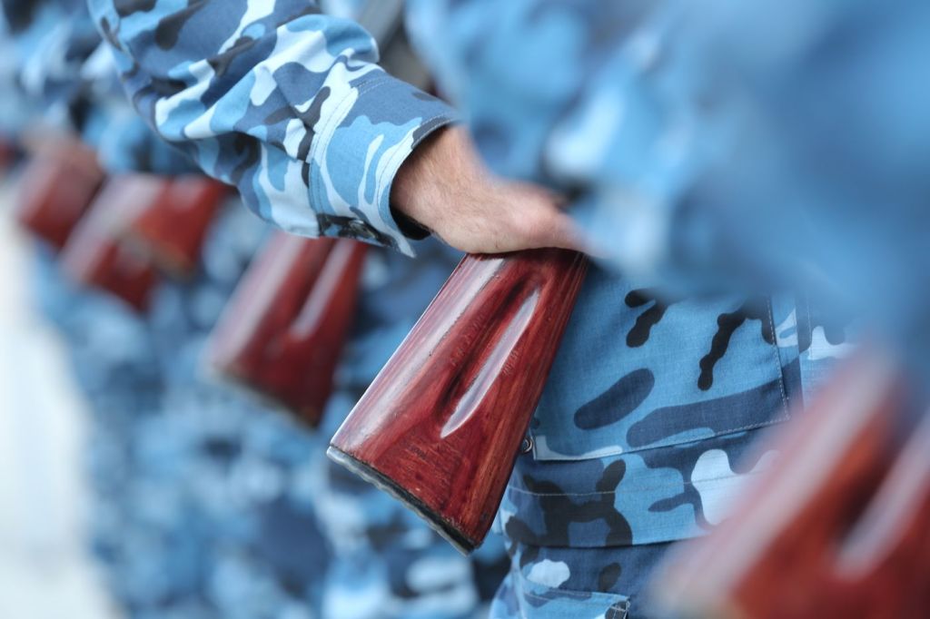 A close view of a wooden shotgun stock held against camouflage