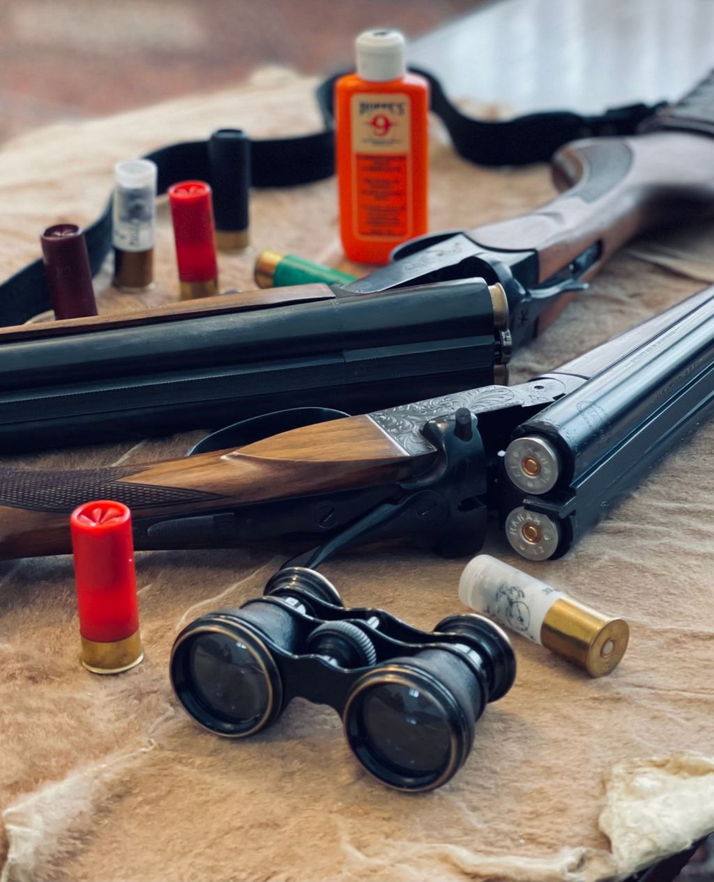 A break-action shotgun with shells and binoculars on a table