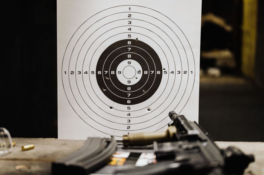 A paper target with a rifle and ammunition on a bench