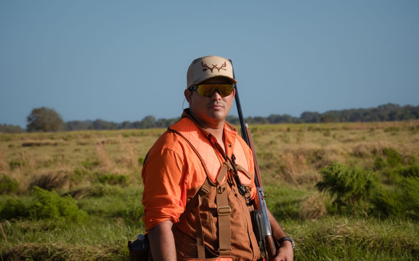 A hunter wearing blaze orange standing in an open field