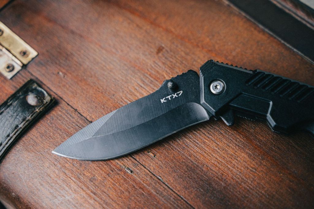 A black folding knife open on a wooden surface