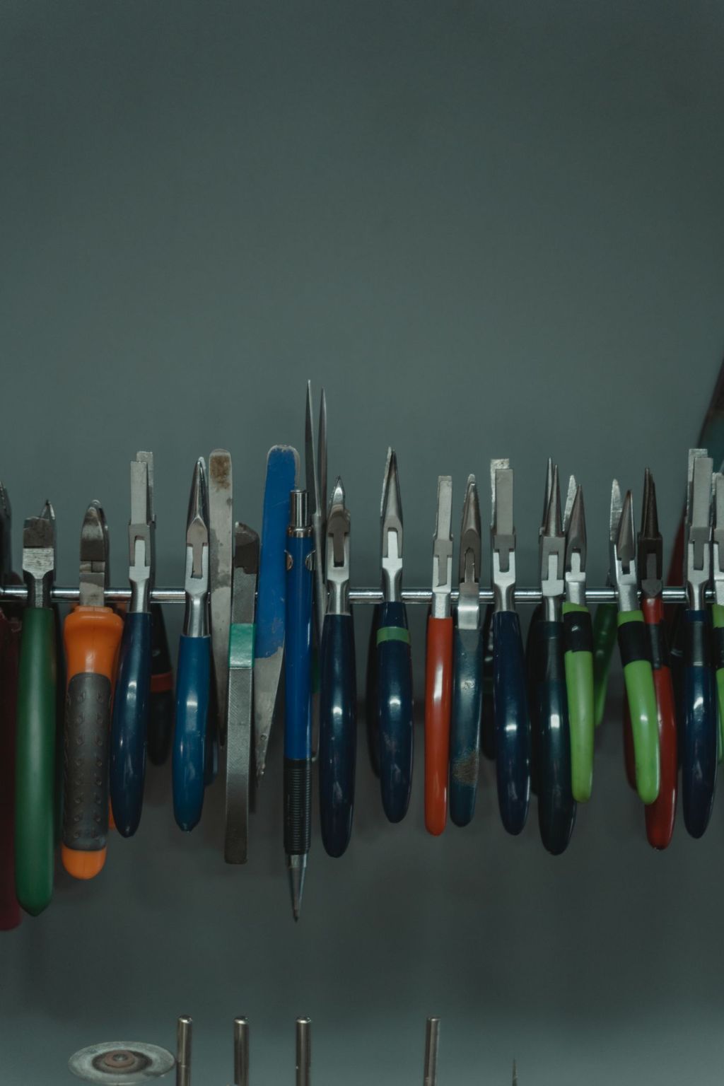 A row of blades with coloured handles on a workshop rack