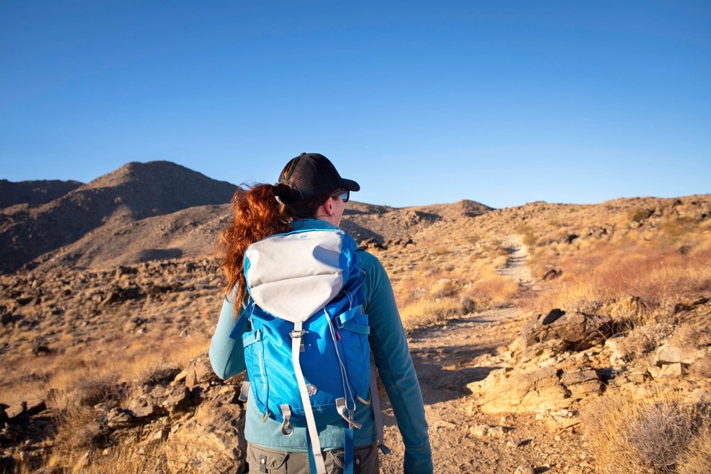 A hiker wearing a backpack looking out over desert terrain