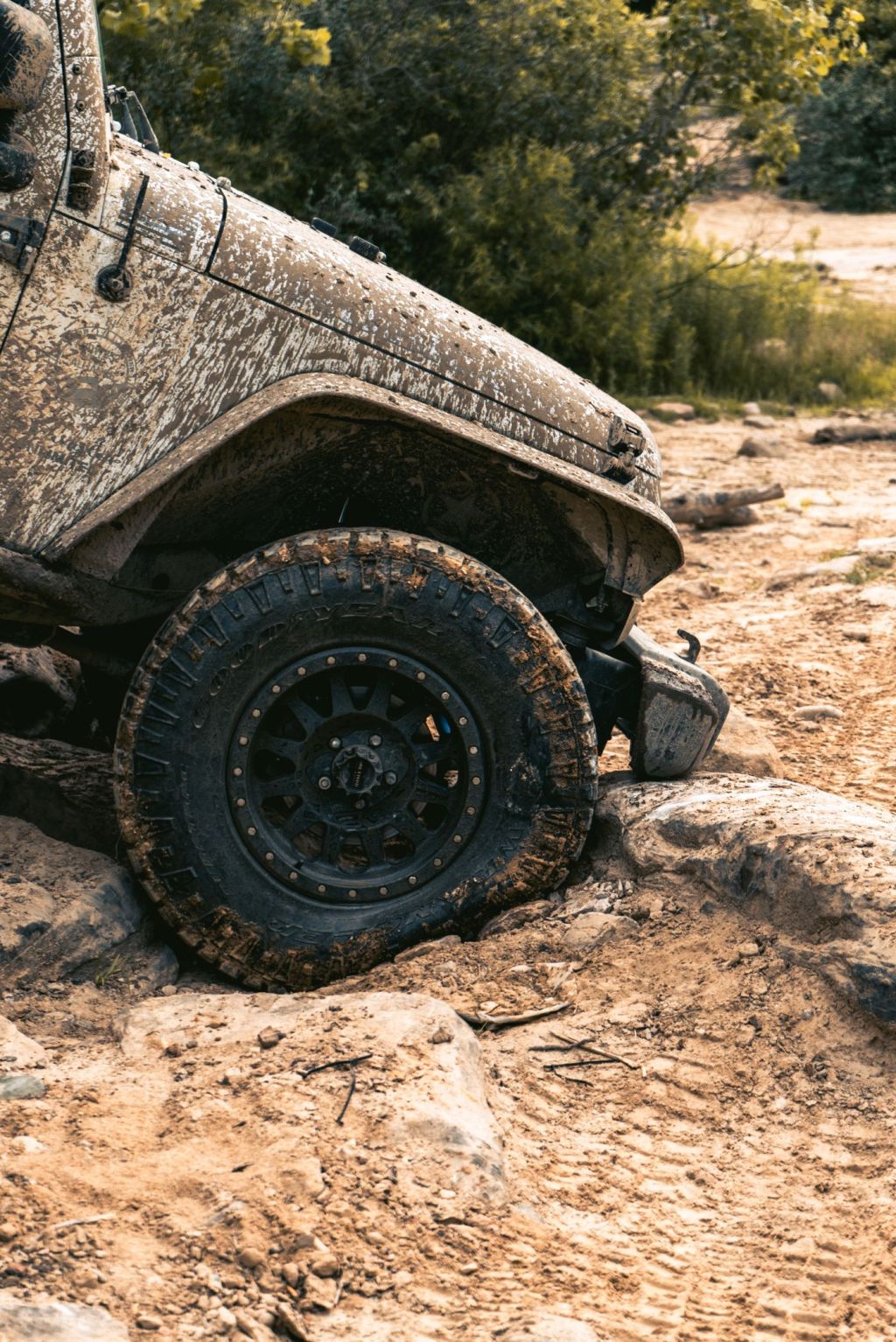 The rear of a mud-covered off-road vehicle with a spare wheel
