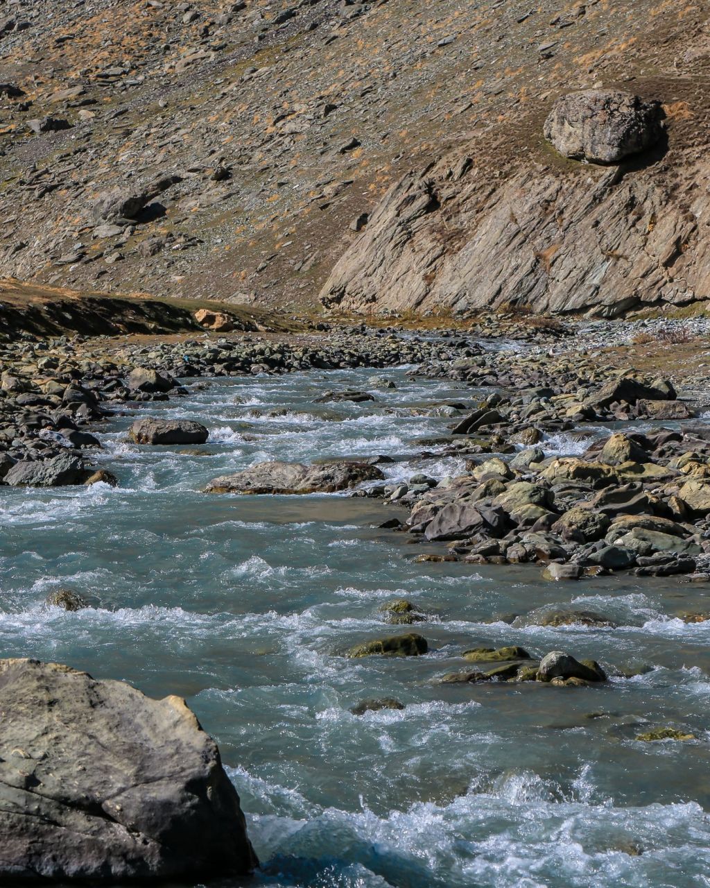 A shallow rocky river running through a mountain valley