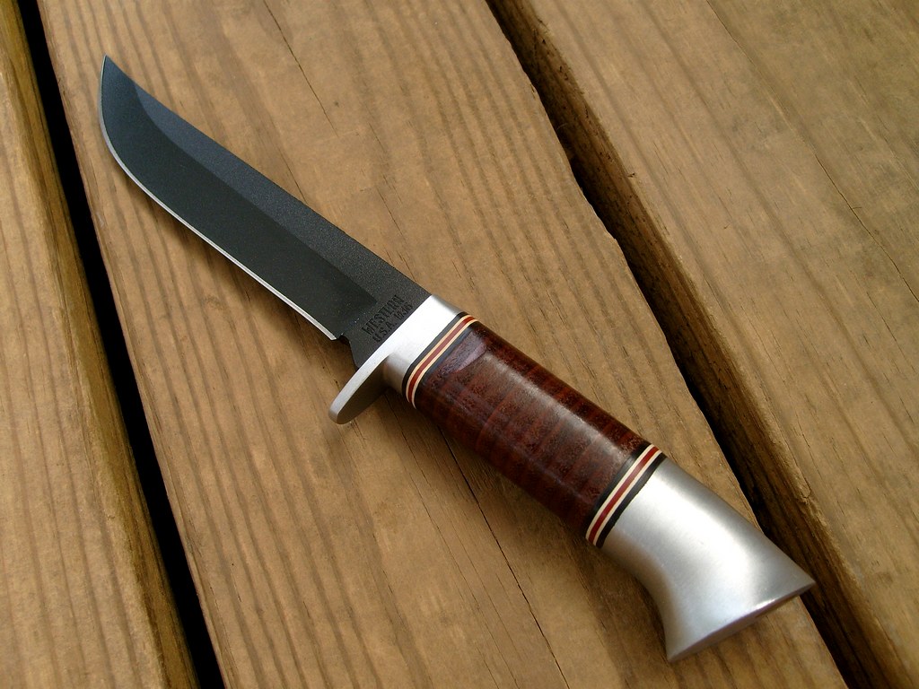 A clip-point fixed-blade knife resting on wooden boards