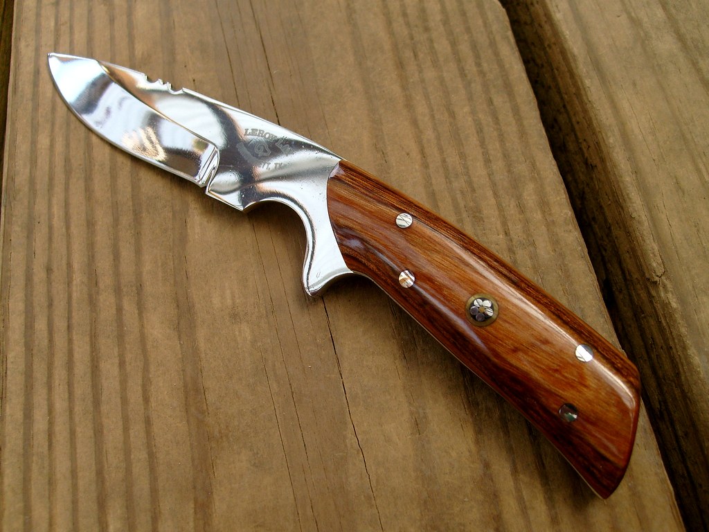 An open folding knife showing the blade and wooden scales