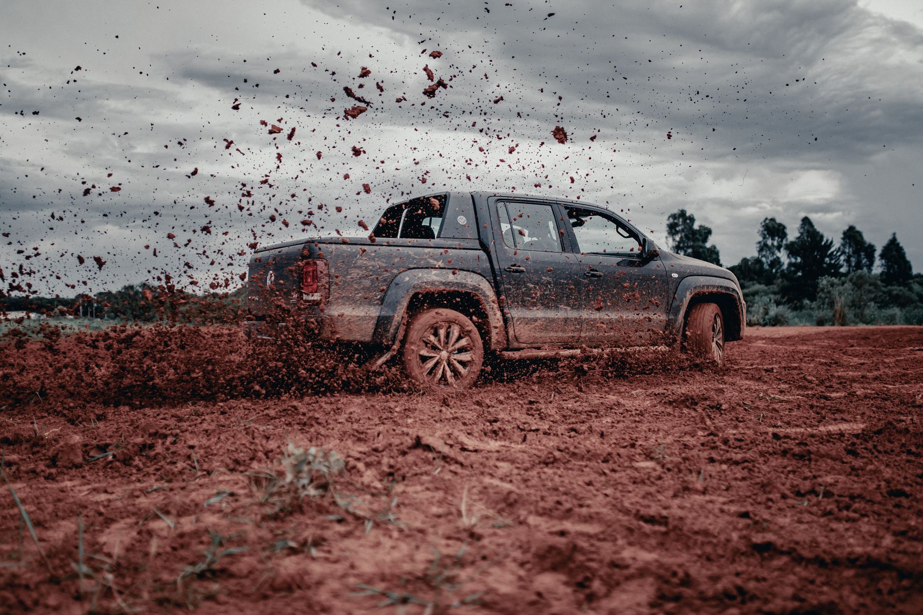 A pickup truck throwing up dirt on a muddy off-road track