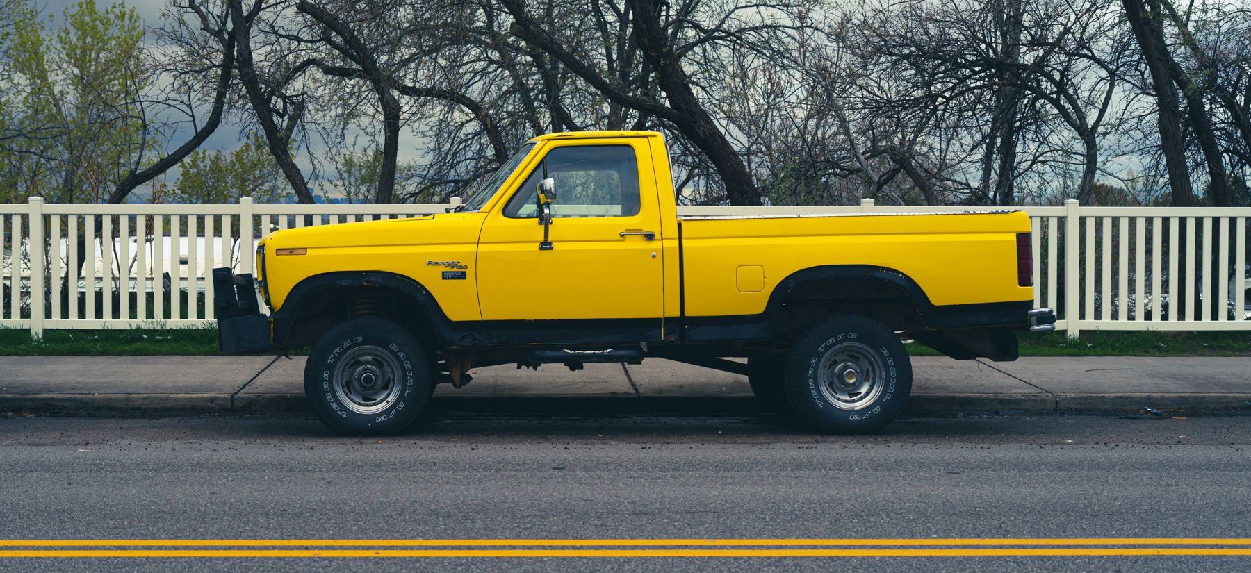 A yellow pickup truck parked beside a road