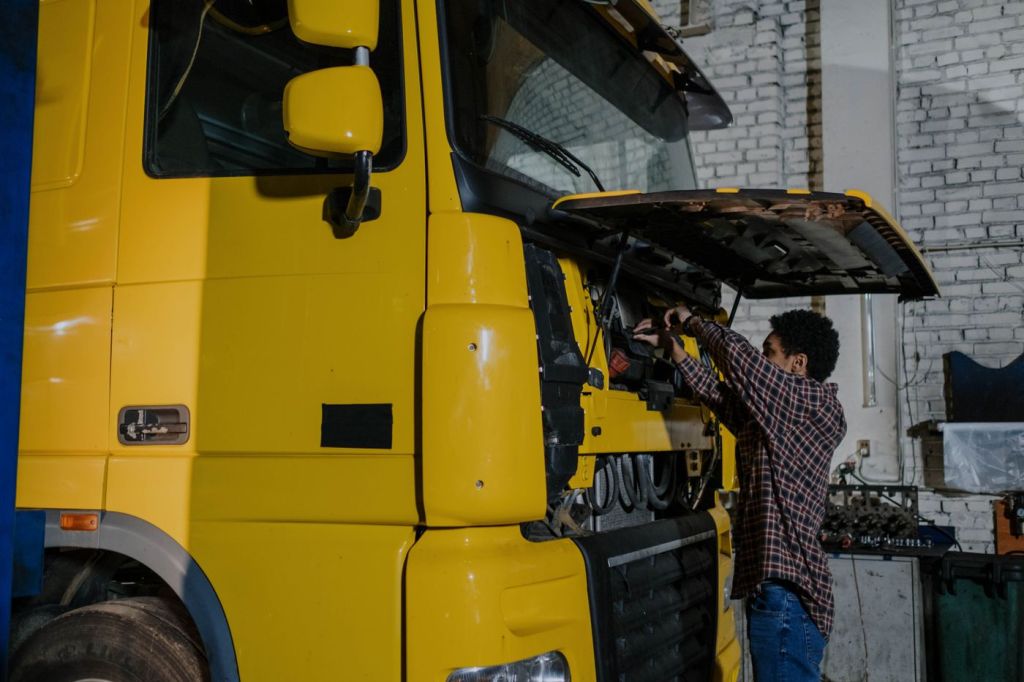 A mechanic working on a truck with the cab open