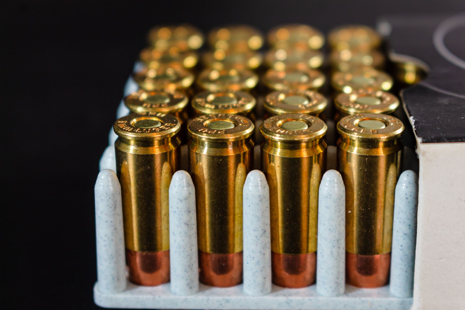 Rifle cartridges with brass cases and copper bullets arranged in a box