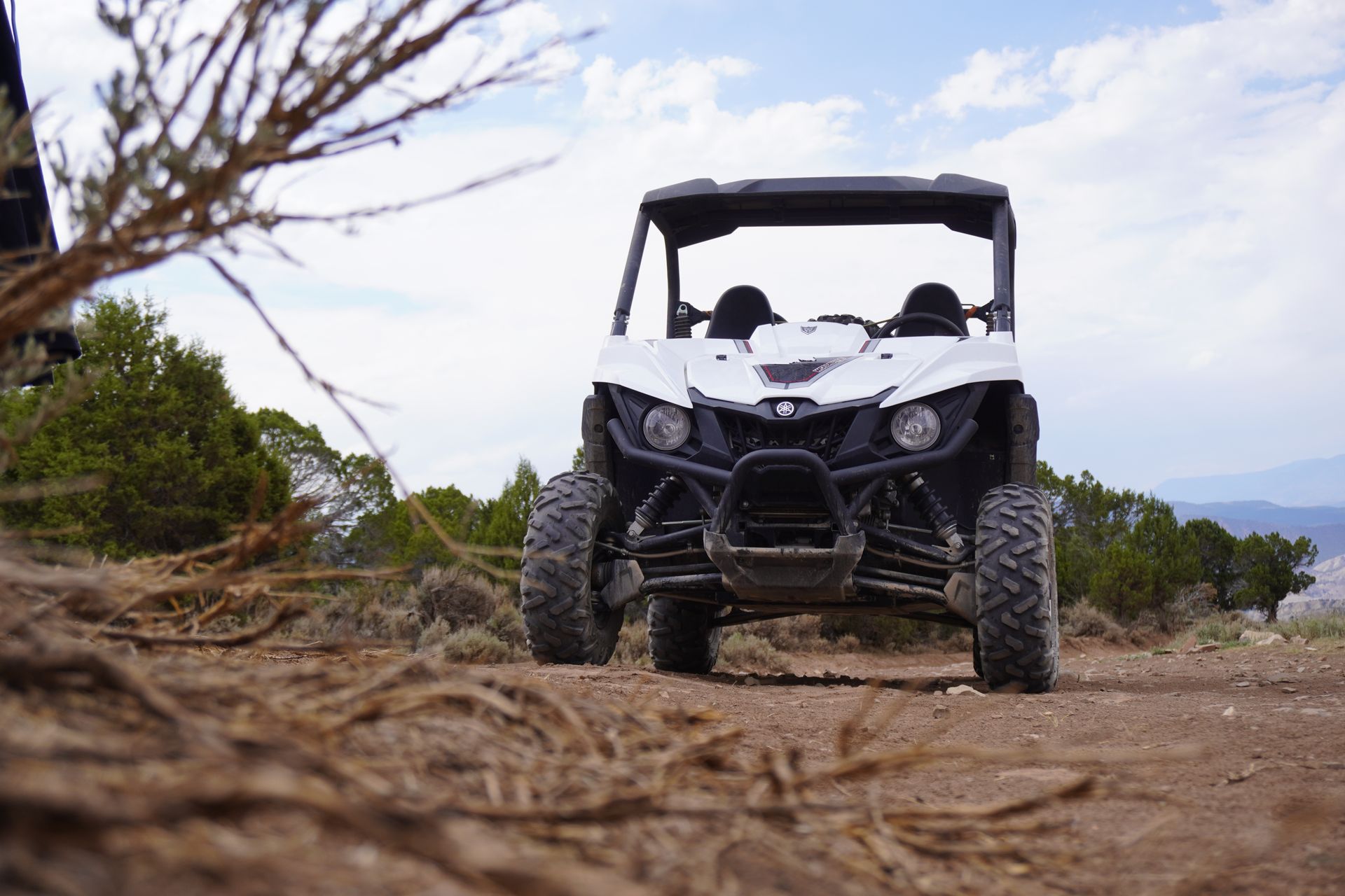 A white side-by-side utility vehicle crossing rough, dry ground