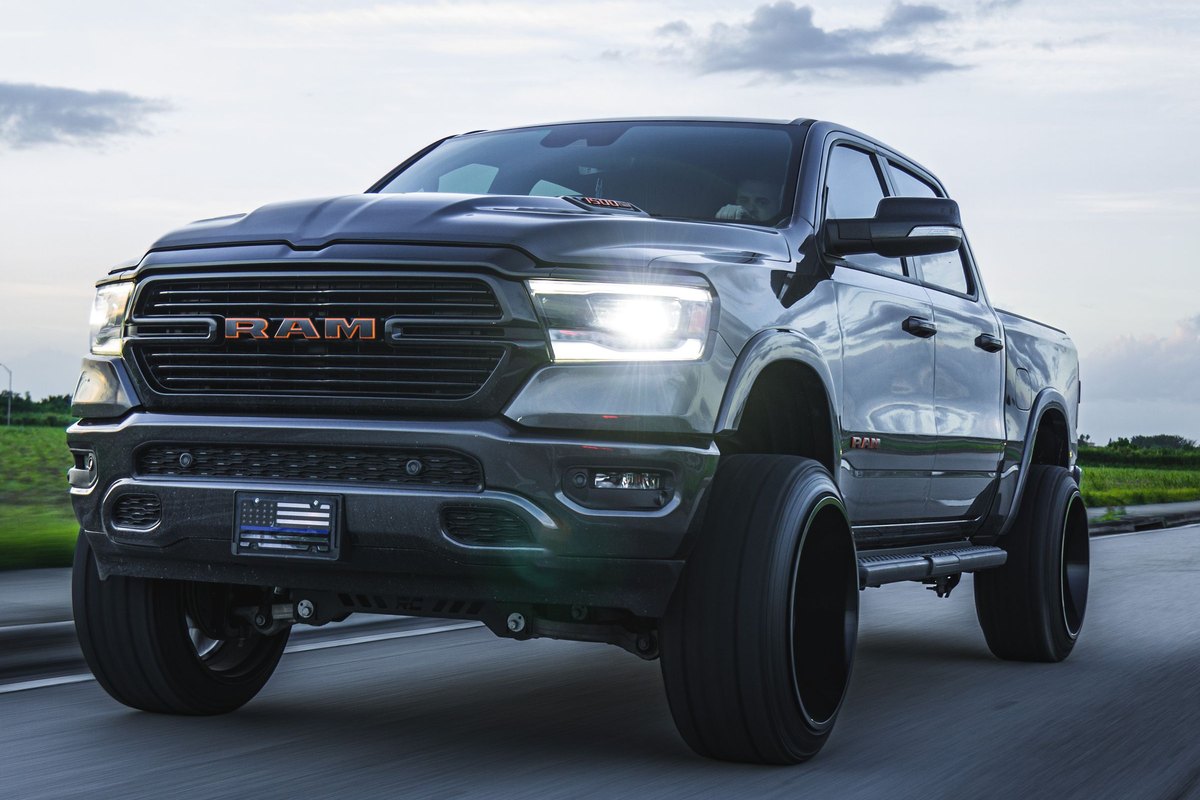 Gray Ram pickup truck with headlights on driving on an open highway
